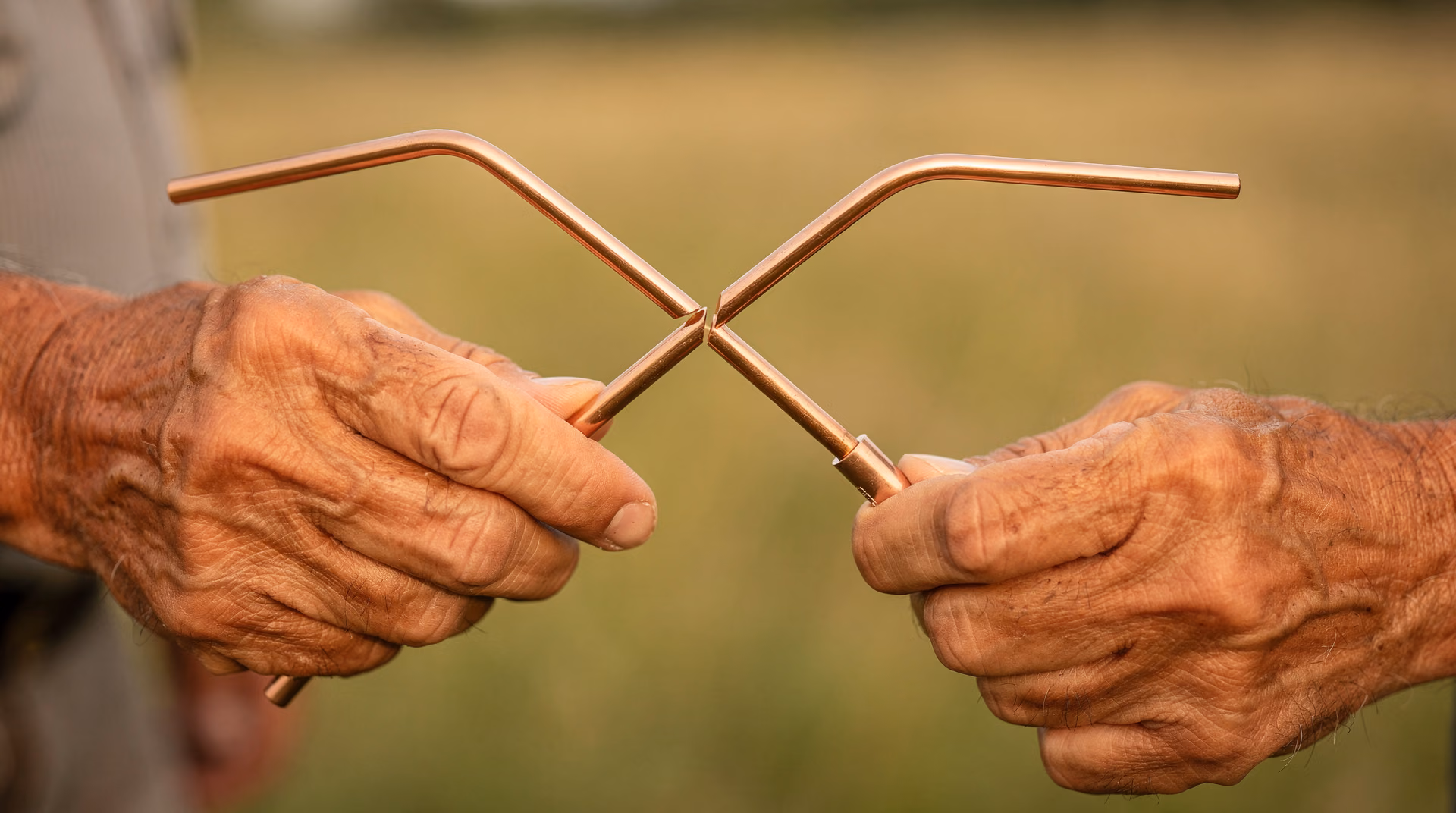 Détail des deux baguettes coudées en cuivre tenues parallèlement par un sourcier en intervention sur un terrain du Sud-Ouest